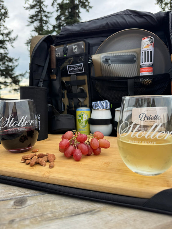 Workspace open on a picnic table with two stemless wine glasses, red grapes and almonds on the bamboo board