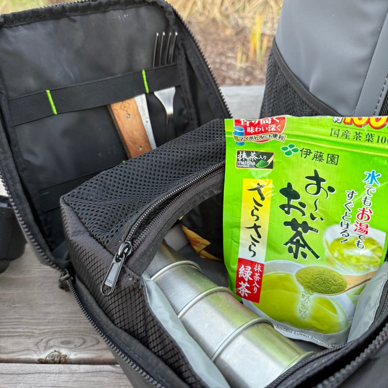 Cold Cube Soft Cooler unzipped with green tea, a thermos and utensils inside