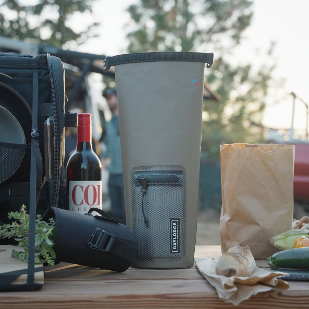 Workspace Camp Collection set up on a tailgate at sunset with the dry bag, plates, mugs and cutting board ready for a camp dinner