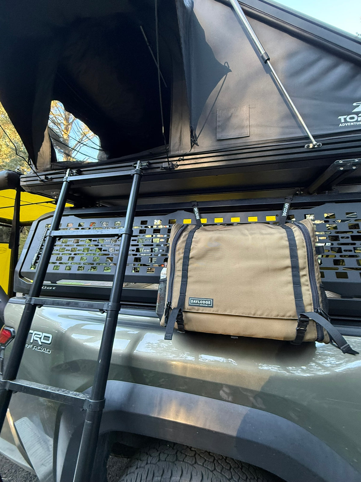 Workspace hanging from a MOLLE panel on a Toyota Tacoma bed rack under a roof-top tent