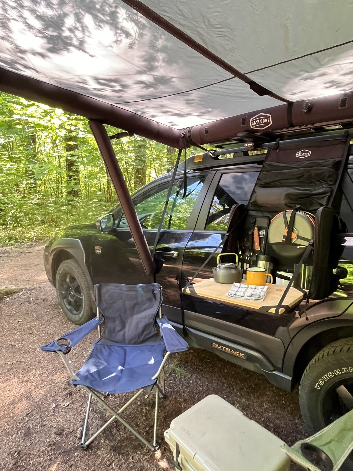 Workspace hanging from a Subaru Outback Wilderness factory rack under an AirHaven awning