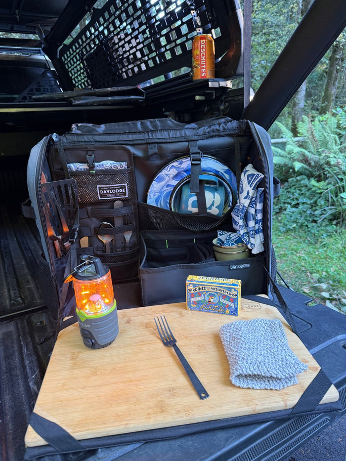 Workspace open on a truck tailgate with a lantern and tinned fish